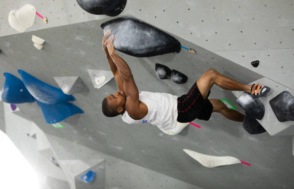 Man climbing overhang wall at Iron City Boulders rock climbing gym