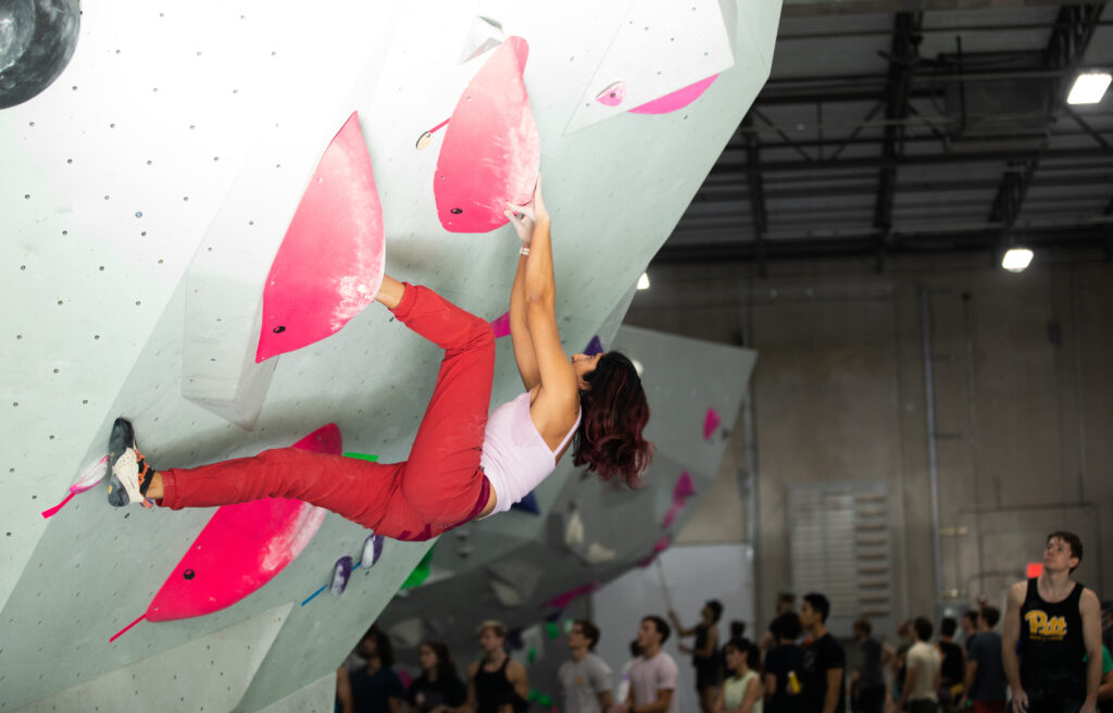 Woman climbing overhang wall at Iron City Boulders rock climbing gym